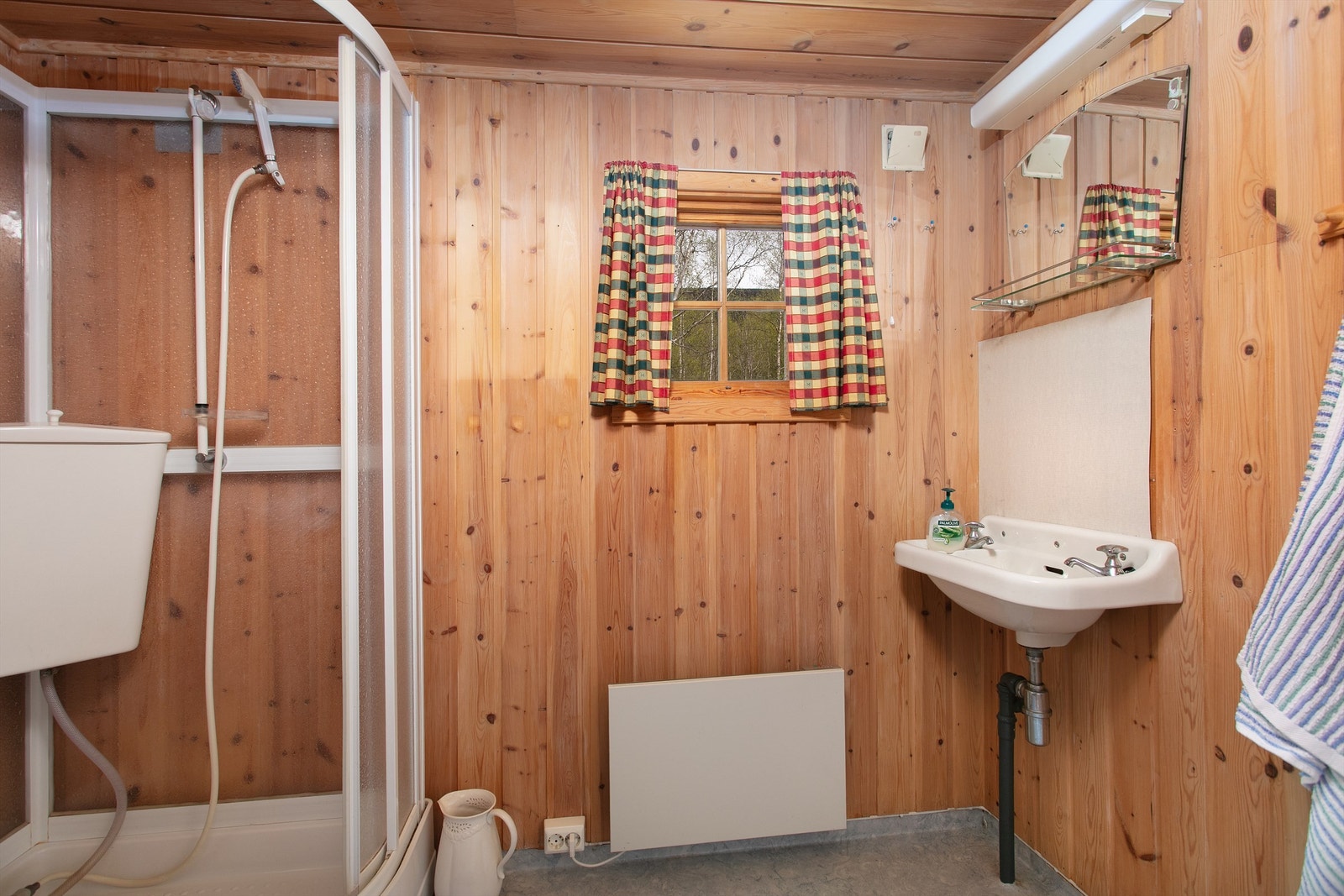 Baderom med dusjkabinett, servant og panelovn. Rommet har vinylbelegg på gulv og avløp for gråvann. Galleribilde