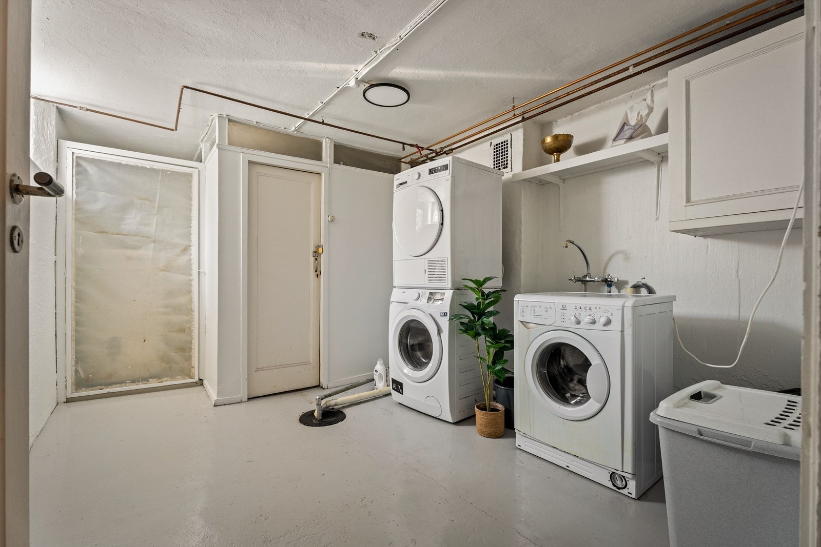 I kjelleren er det et meget romslig og delikat vaskerom for de to leilighetene. Her kan du ha både vaskemaskin og tørketrommel. Boden rett frem (den med hengelås) tilhører leiligheten. Galleribilde