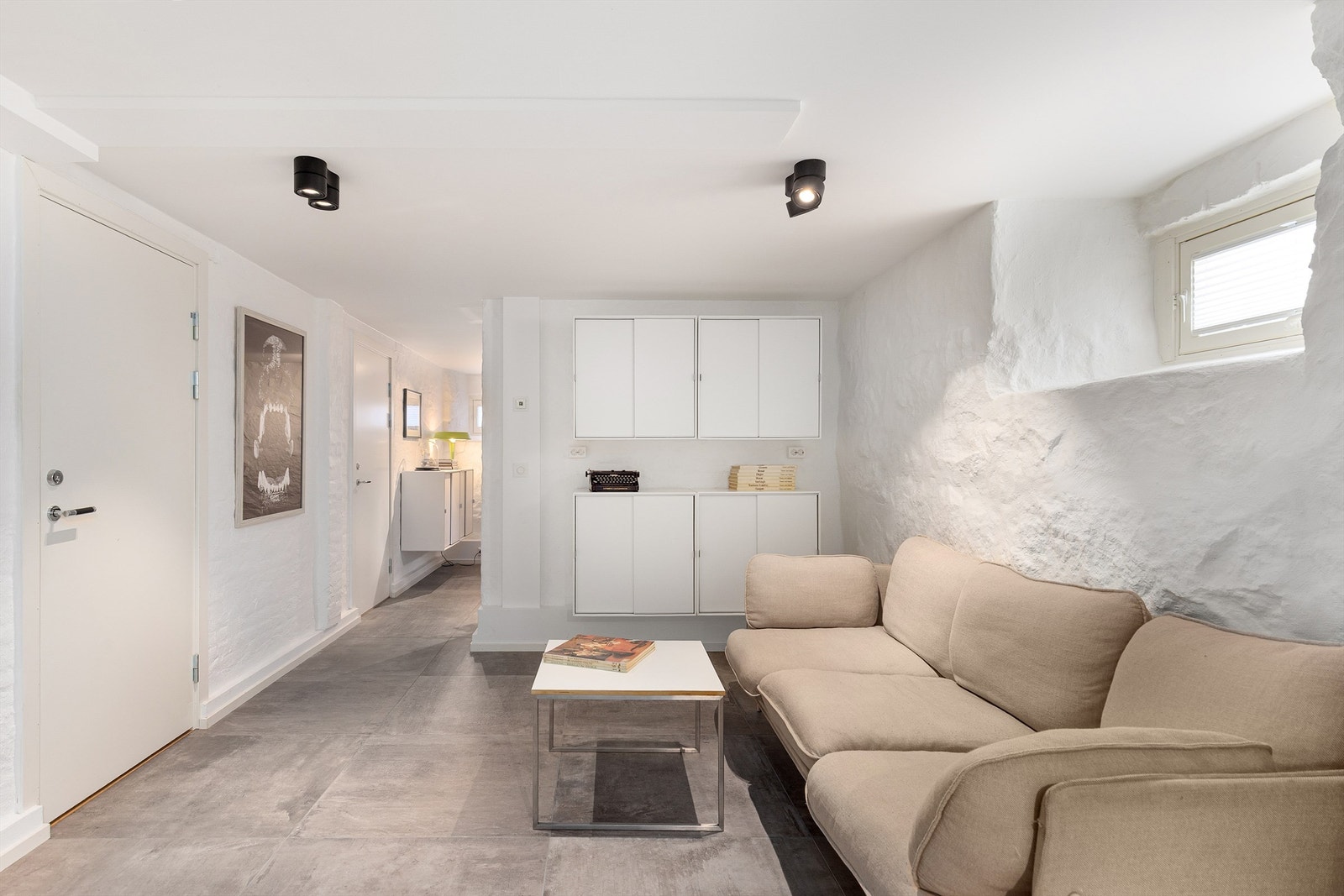 Det er idag innredet som en ys og moderne kjellerstue. Men det er lagt klart for vann i veggen der skapene henger om man skulle ønske å etablere et kjøkken Galleribilde