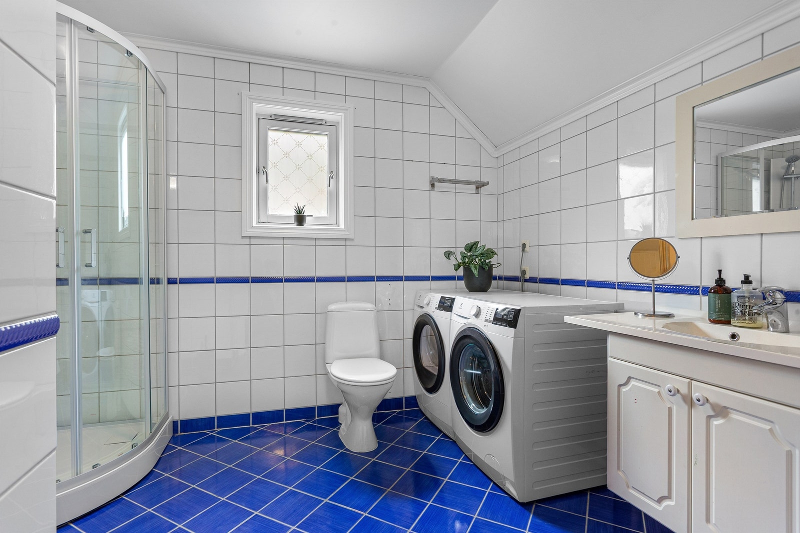 Badet er fra byggeåret og er utstyrt med gulvstående toalett, dusjkabinett samt servantinnredning. Galleribilde