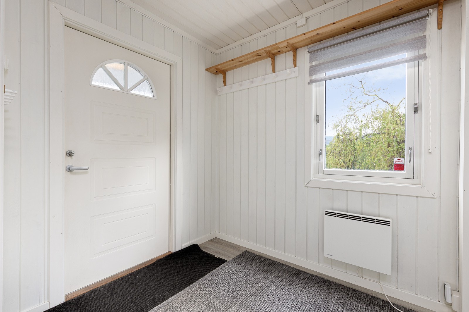 Entréen er et tilbygg fra 1973 og har malte panelvegger og plass til yttertøy. Galleribilde