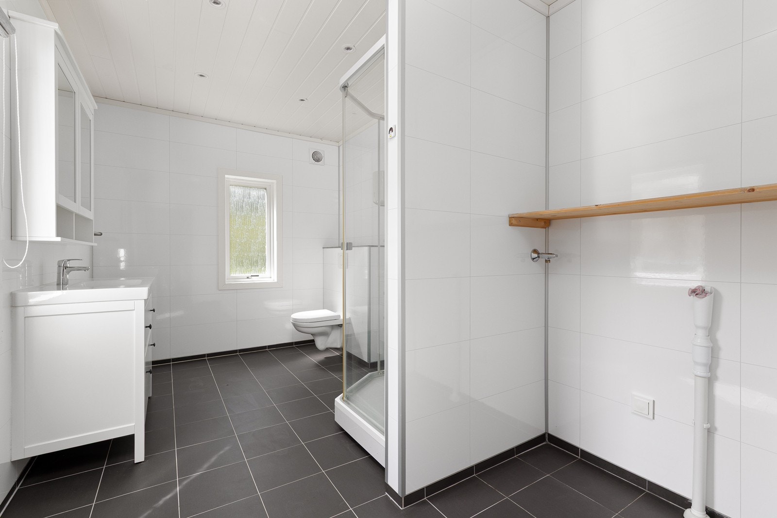 Badet har baderomsplater på veggene og opplegg for vaskemaskin. Galleribilde