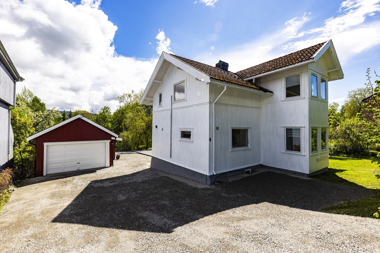 Eiendommen har en romslig, gruset gårdsplass med en frittliggende garasje. Galleribilde