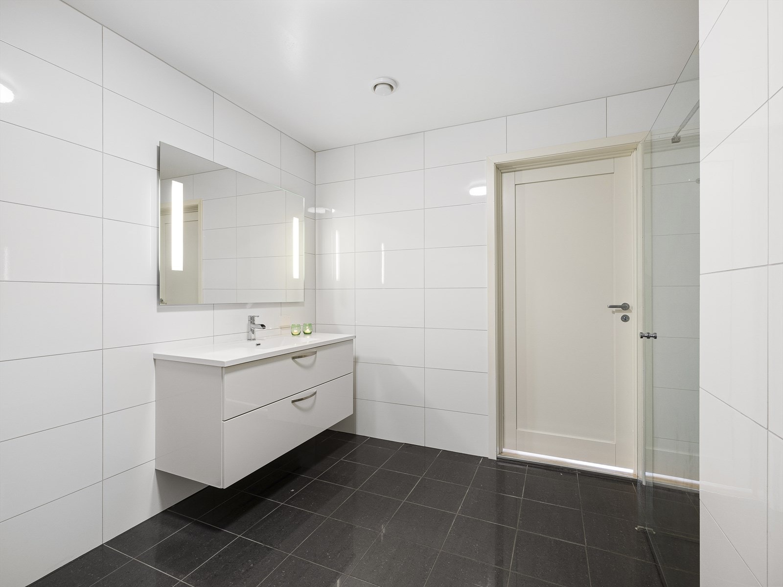 Badet i andre etasje er romslig, moderne og tidløst innredet med store fliser i stilrene fargetoner. Galleribilde