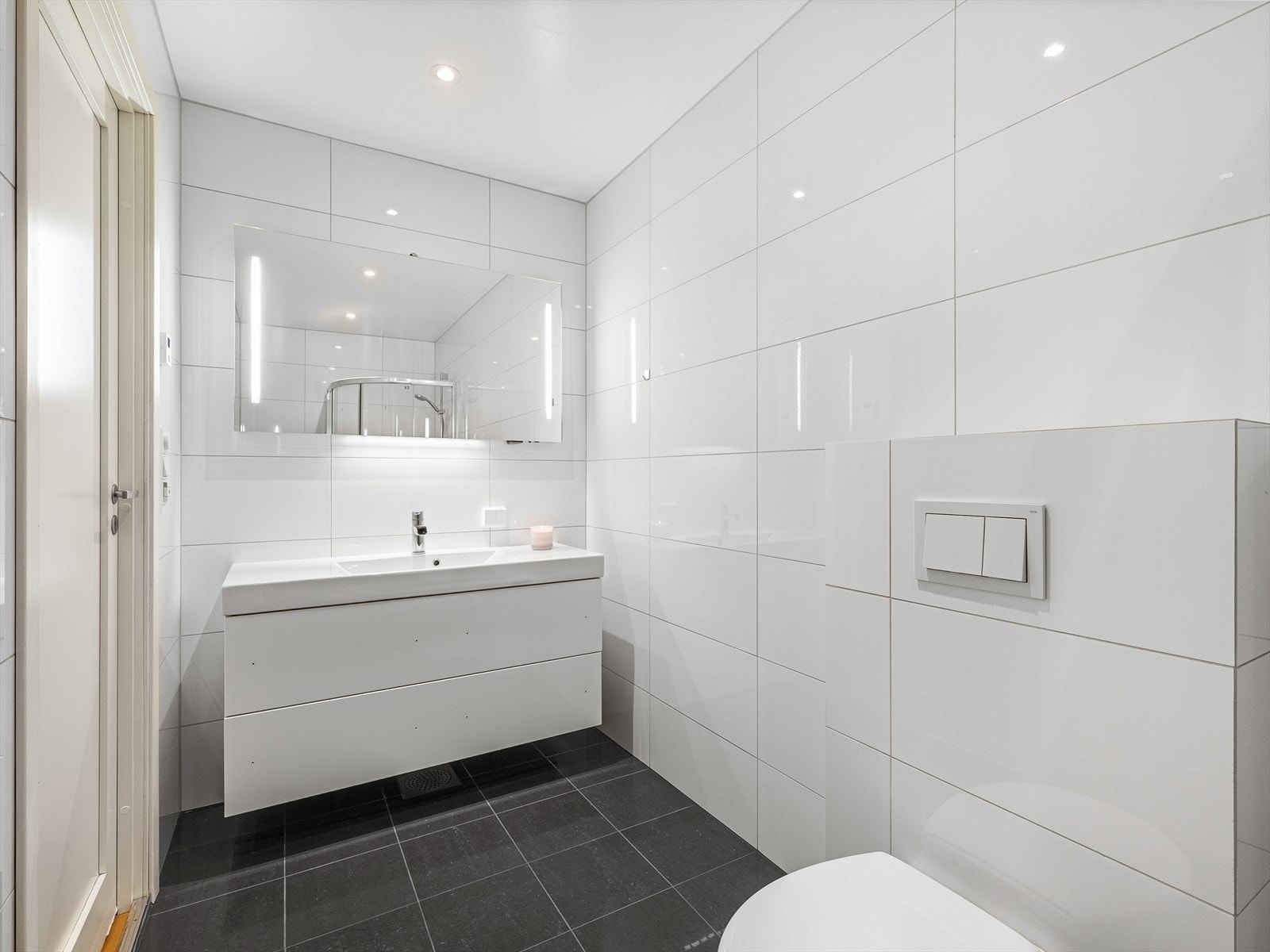Badet er utstyrt med dusj, servant og vegghengt toalett. Galleribilde