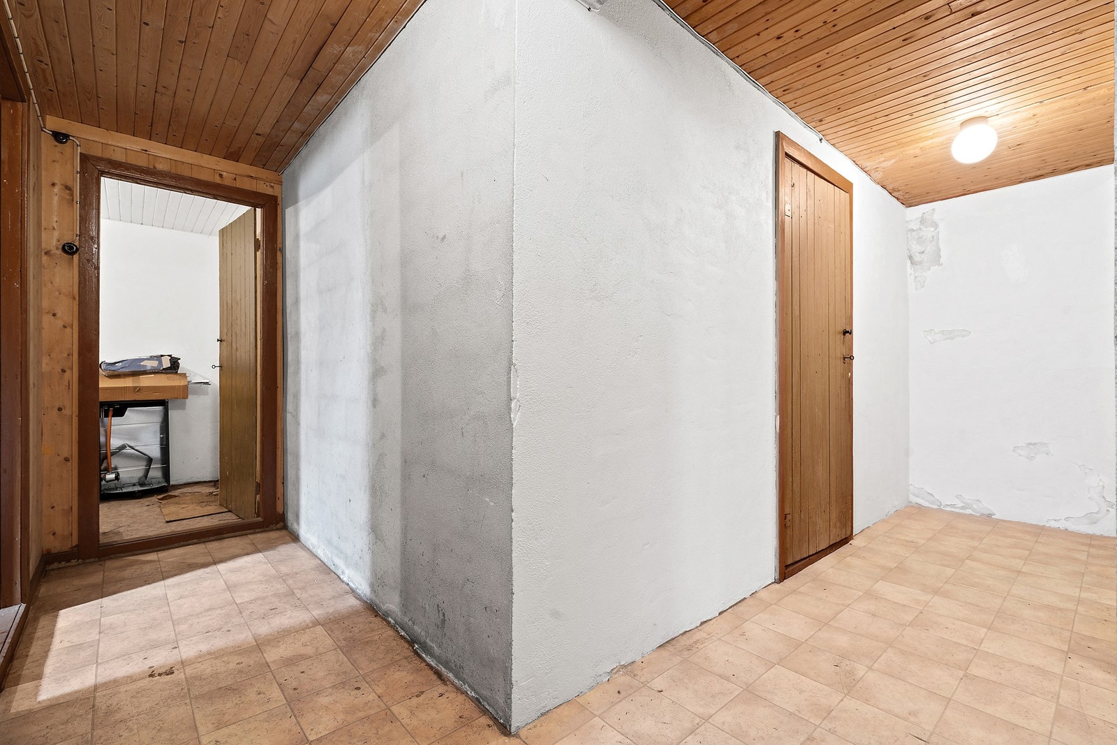Gangareal i kjelleren med panelkledde dører inn til bodene. Galleribilde