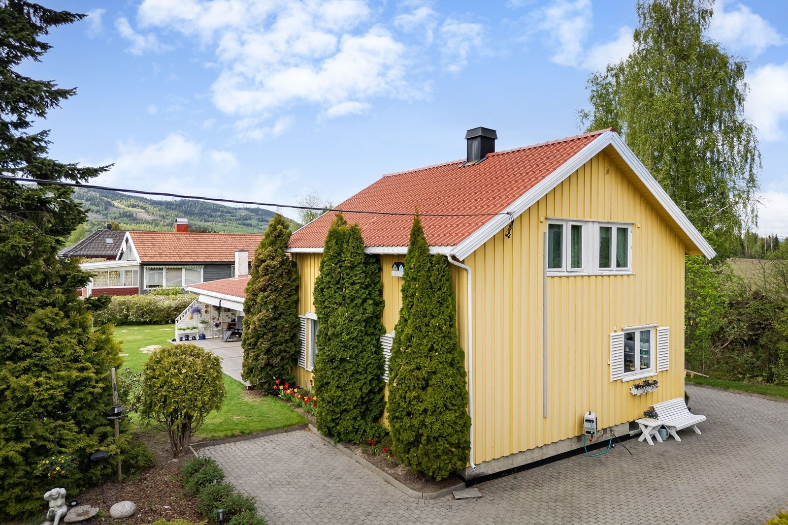Tomten er pent opparbeidet med hage og beplantning, i tillegg til steinlagt gårdsplass. Galleribilde