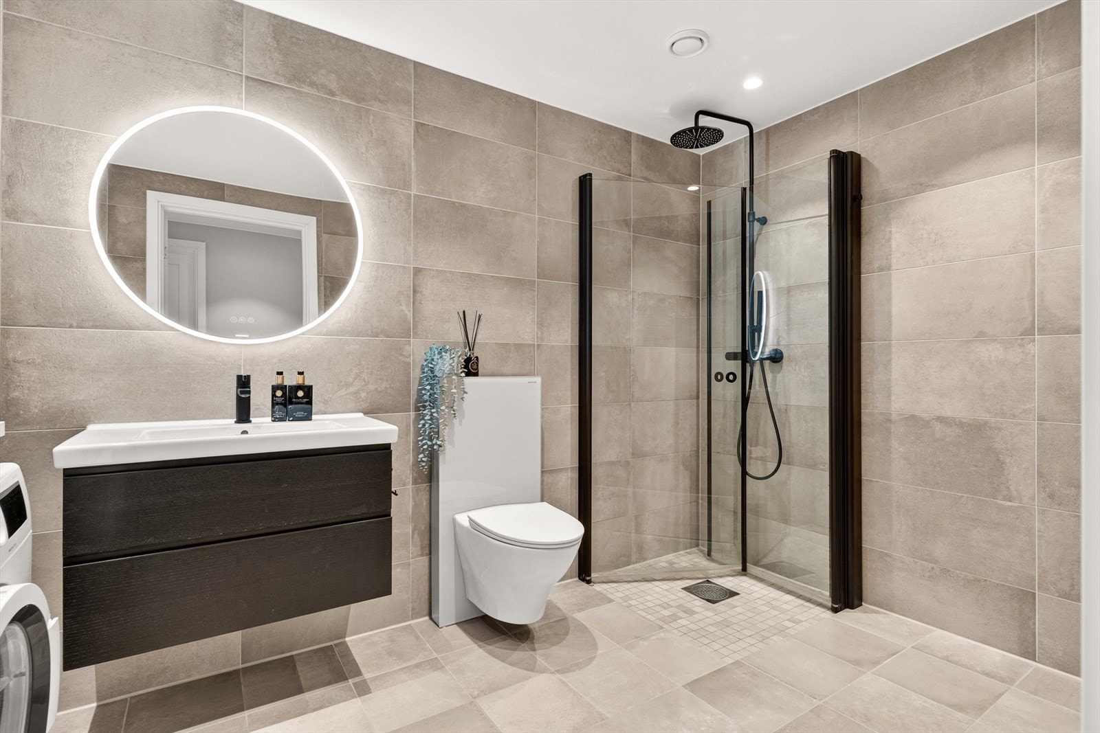 Badet er delikat innredet med store, grå fliser på gulv og vegger. I gulvet har man også vannbåren varme for ekstra komfort. Galleribilde