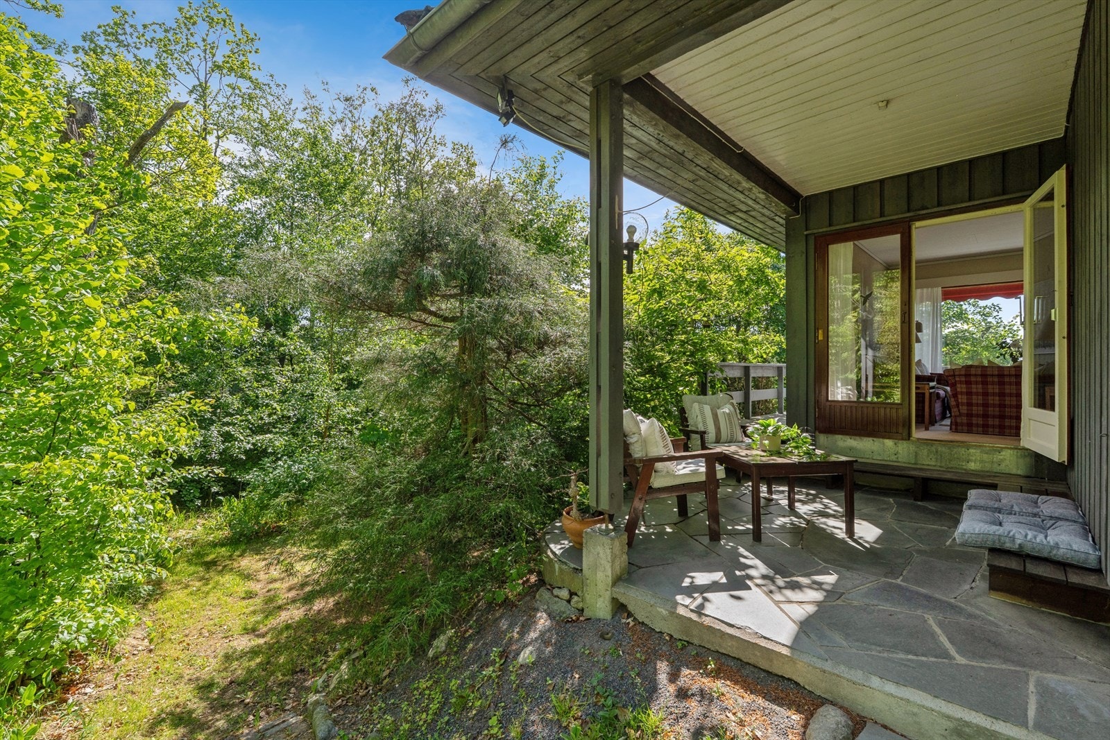 Terrasse med betongdekke og skiferfliser, med direkte utgang fra stuen. Galleribilde