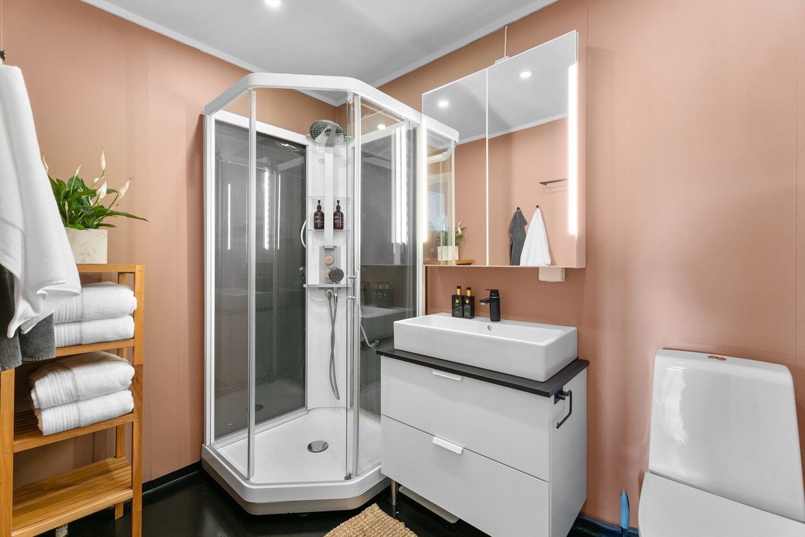 Badet holder en enkel, men fin standard med malte våtromsplater, malt vinyl, wc, dusjkabinett og servantskap. Galleribilde