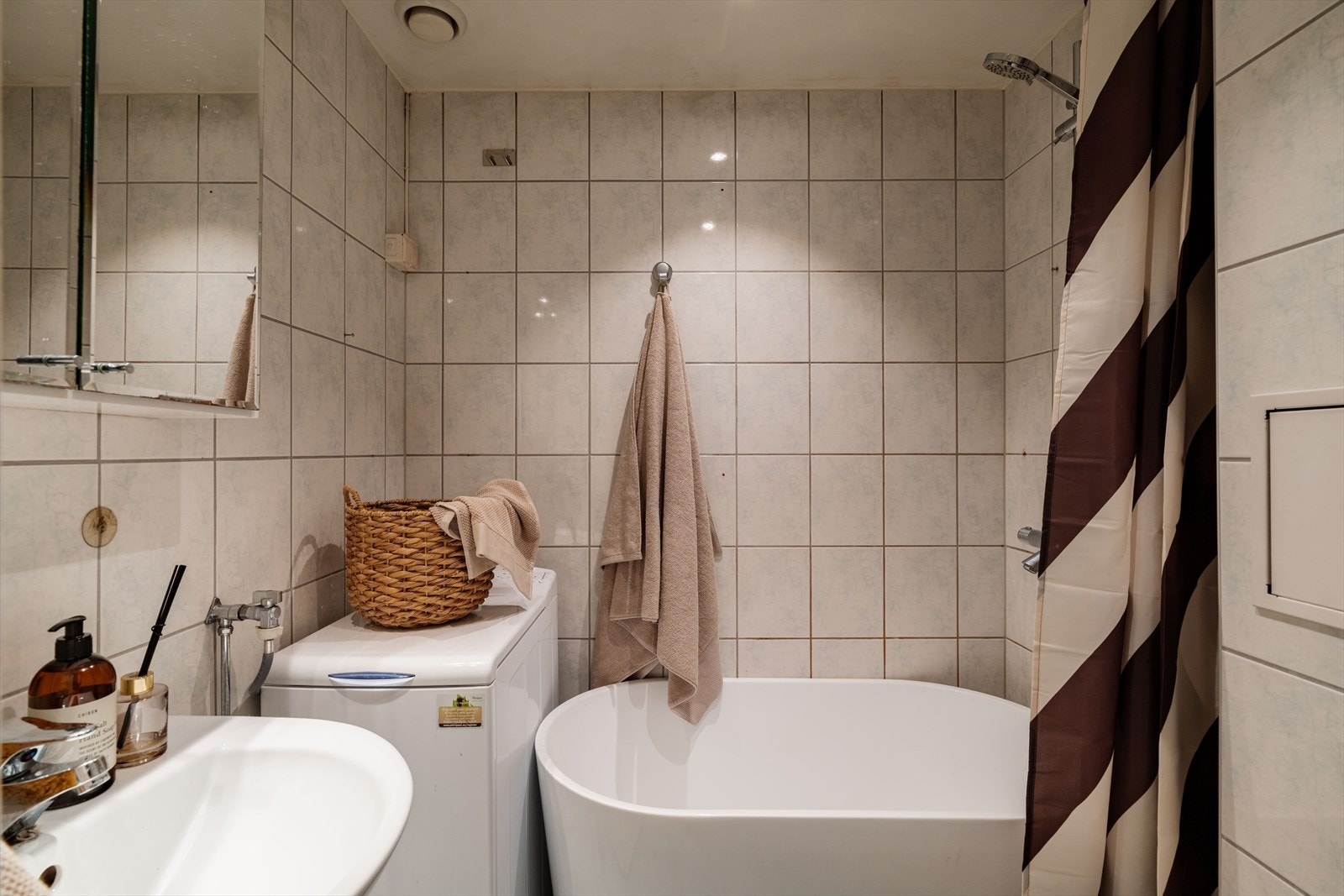 Badet er innredet med servant med servantskap, speilskap, klosett og badekar med dusjarmatur på vegg. Galleribilde