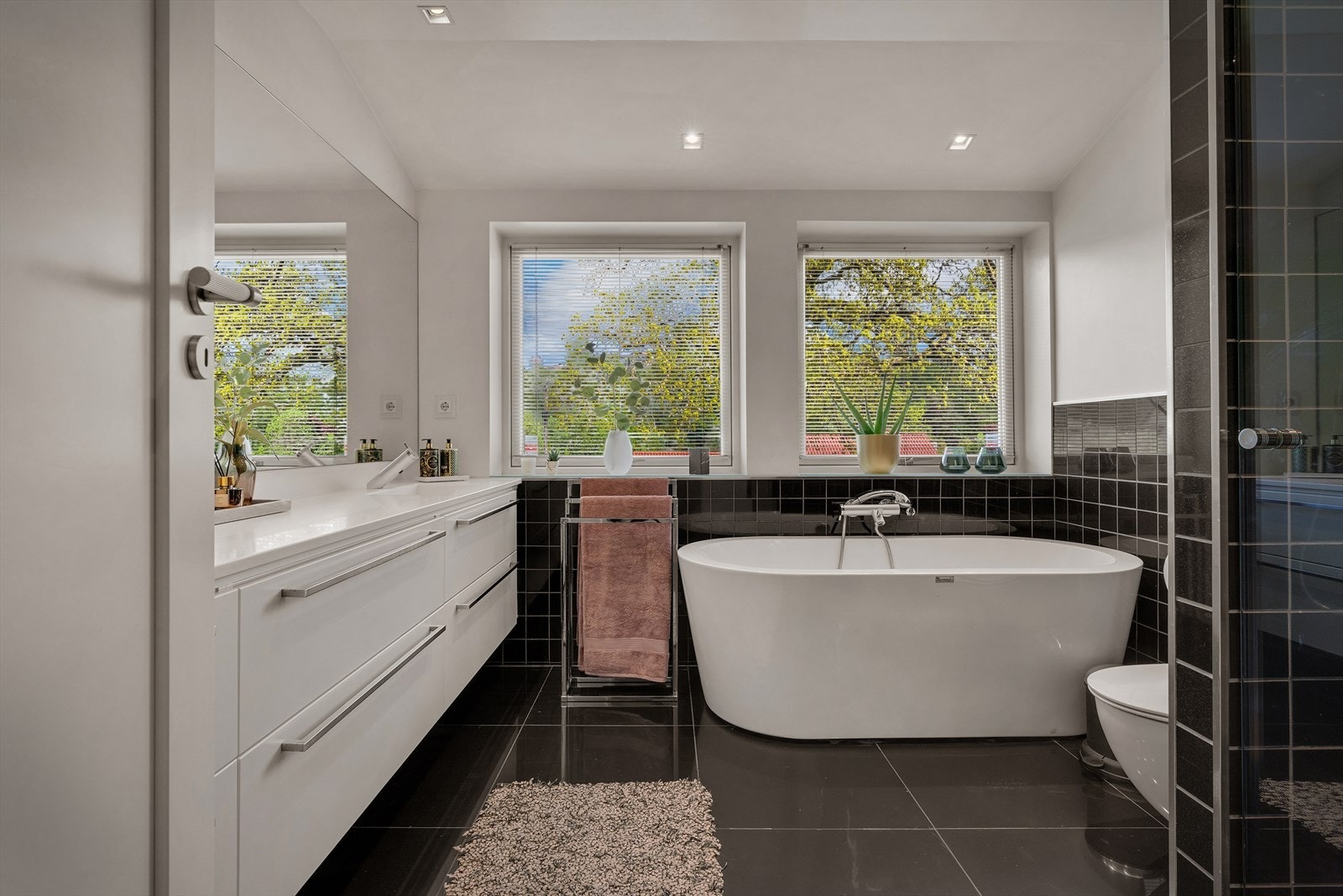 Det ene badet er på 8,4 m² og fremstår som et romslig familiebad med dobbel servant, veggmontert toalett, badekar og dusjhjørne. Galleribilde
