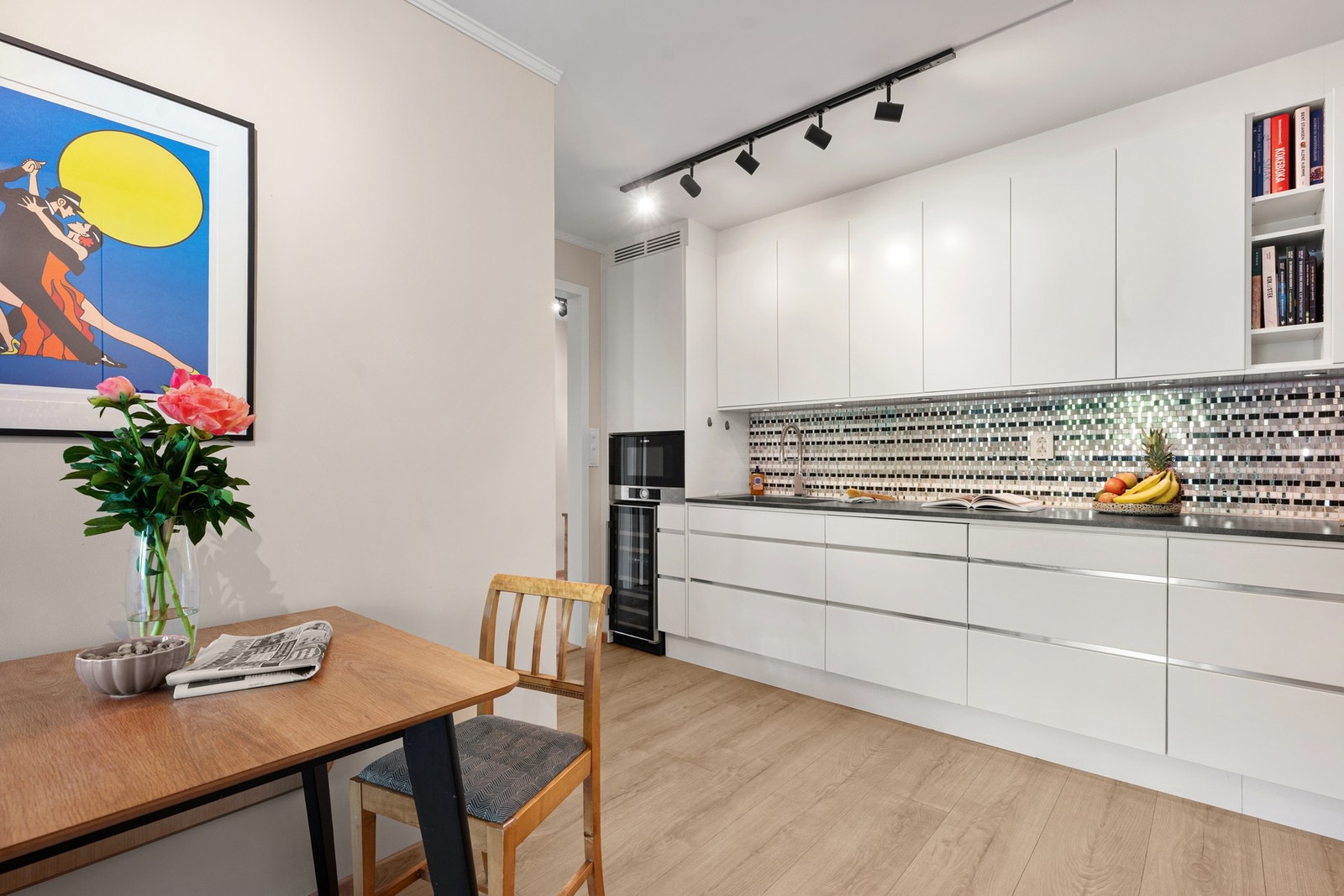 Den lyse kjøkkeninnredningen gir et rent og tidløst uttrykk, med fliser over benk, benkebelysning og godt med oppbevaringsplass. Galleribilde