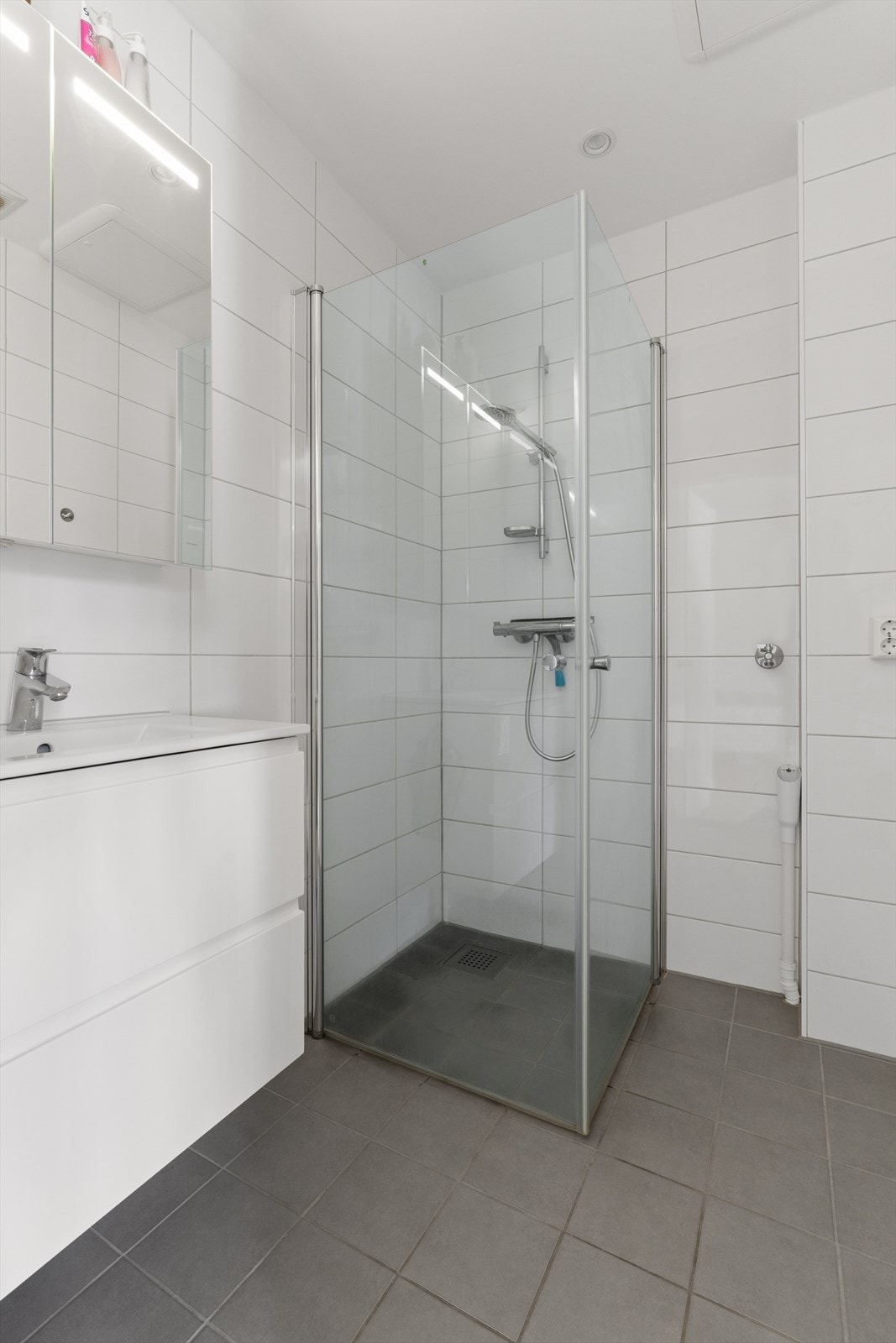 Baderomsinnredningen består av servant med skuffeseksjon, speilskap med overlys, dusjhjørne med svingbare glassdører og opplegg for vaskemaskin. Galleribilde