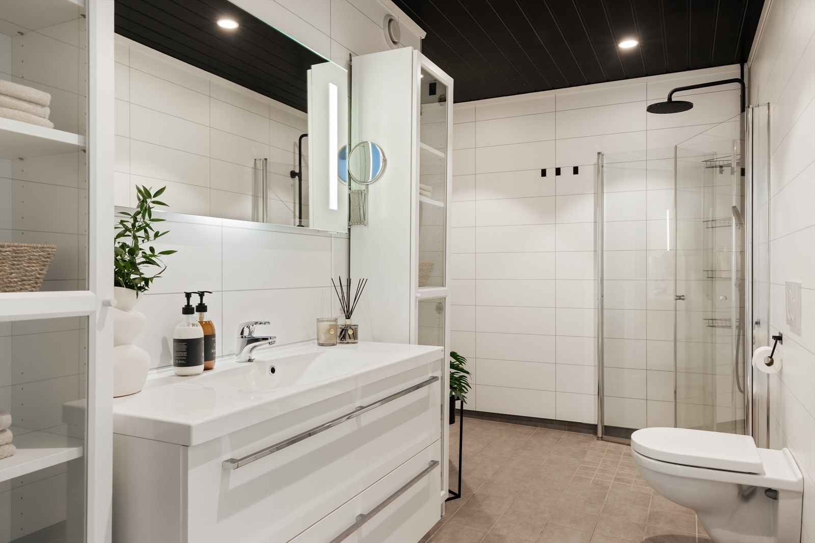 Badet er av god størrelse og inneholder baderomsinnredning med nedfelt servant, høyskap, vegghengt toalett, dusjvegger og opplegg for vaskemaskin Galleribilde
