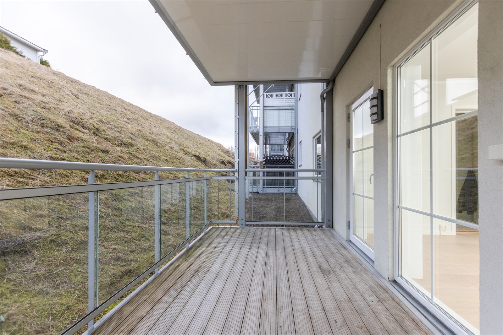 Leiligheten har utgang til en vestvendt og overbygget balkong. Balkongen har spaltegulv av tre og et rekkverk i metall og glass. Balkongen har ellers utebelysning og en stikkontakt. Galleribilde