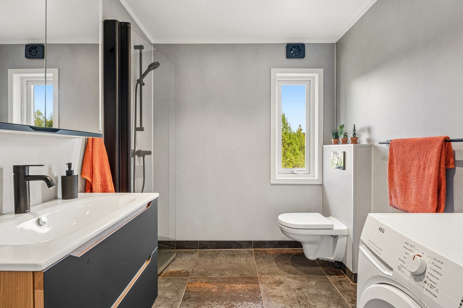 Badet er innredet med baderomsinnredning med heldekkende servant og underskap med skuffer, veggmontert toalett samt dusjhjørne med glassvegger/-dør i herdet glass. Det er i tillegg opplegg for vaskemaskin med tappekran og avløp. Galleribilde