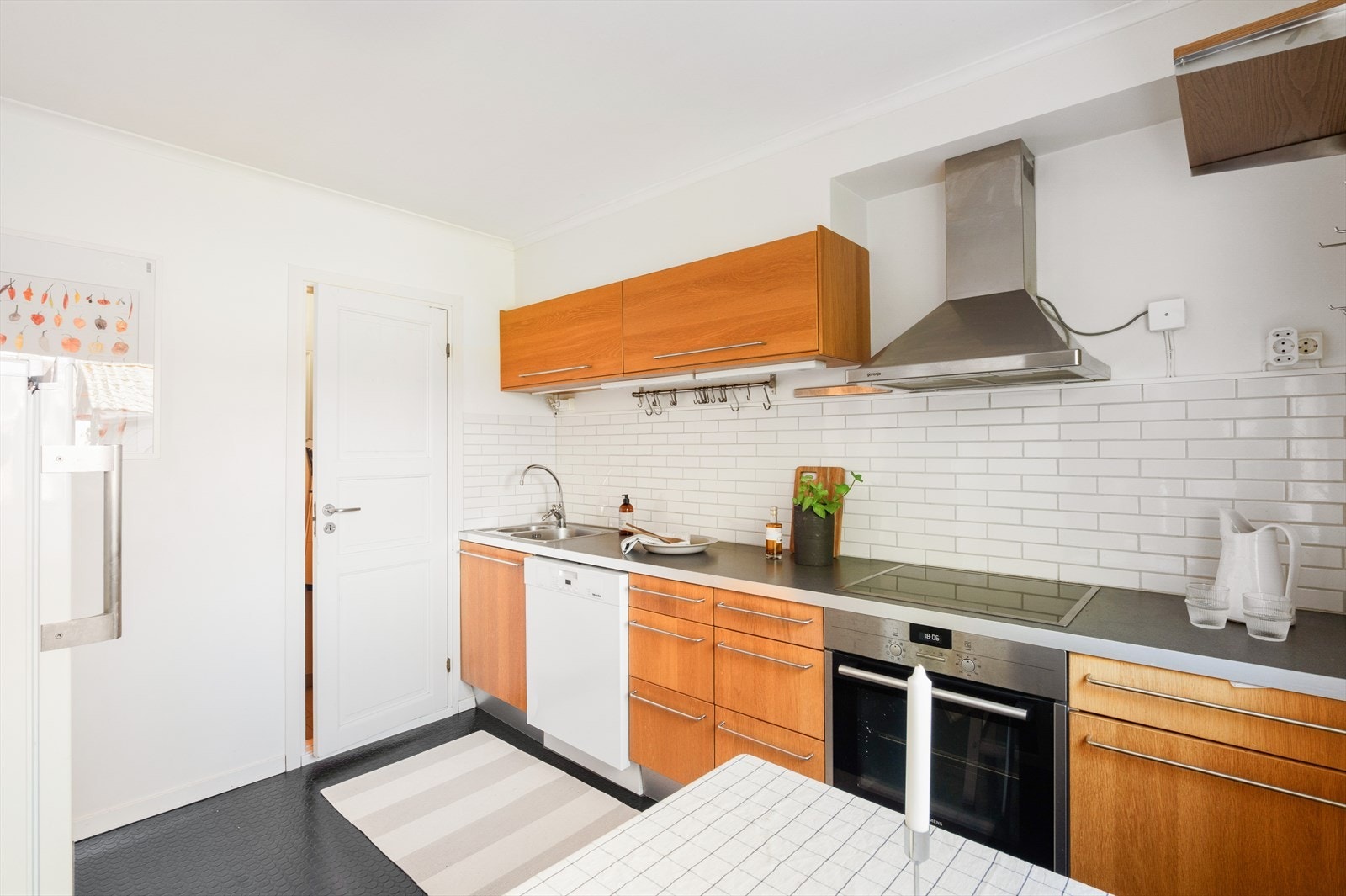 Kjøkkeninnredning med glatte fronter og laminatbenkeplate. Rommet er utstyrt med oppvaskmaskin, platetopp og stekeovn. Galleribilde