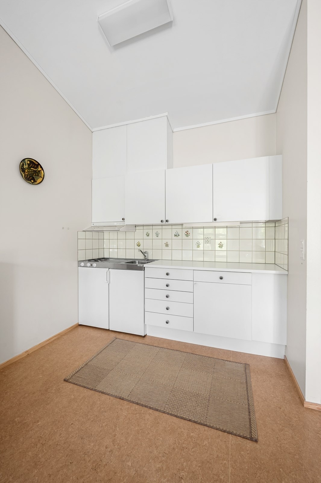 Kjøkkeninnredning med glatte fronter, laminert benkeplate, platetopp og kjøleskap. Galleribilde