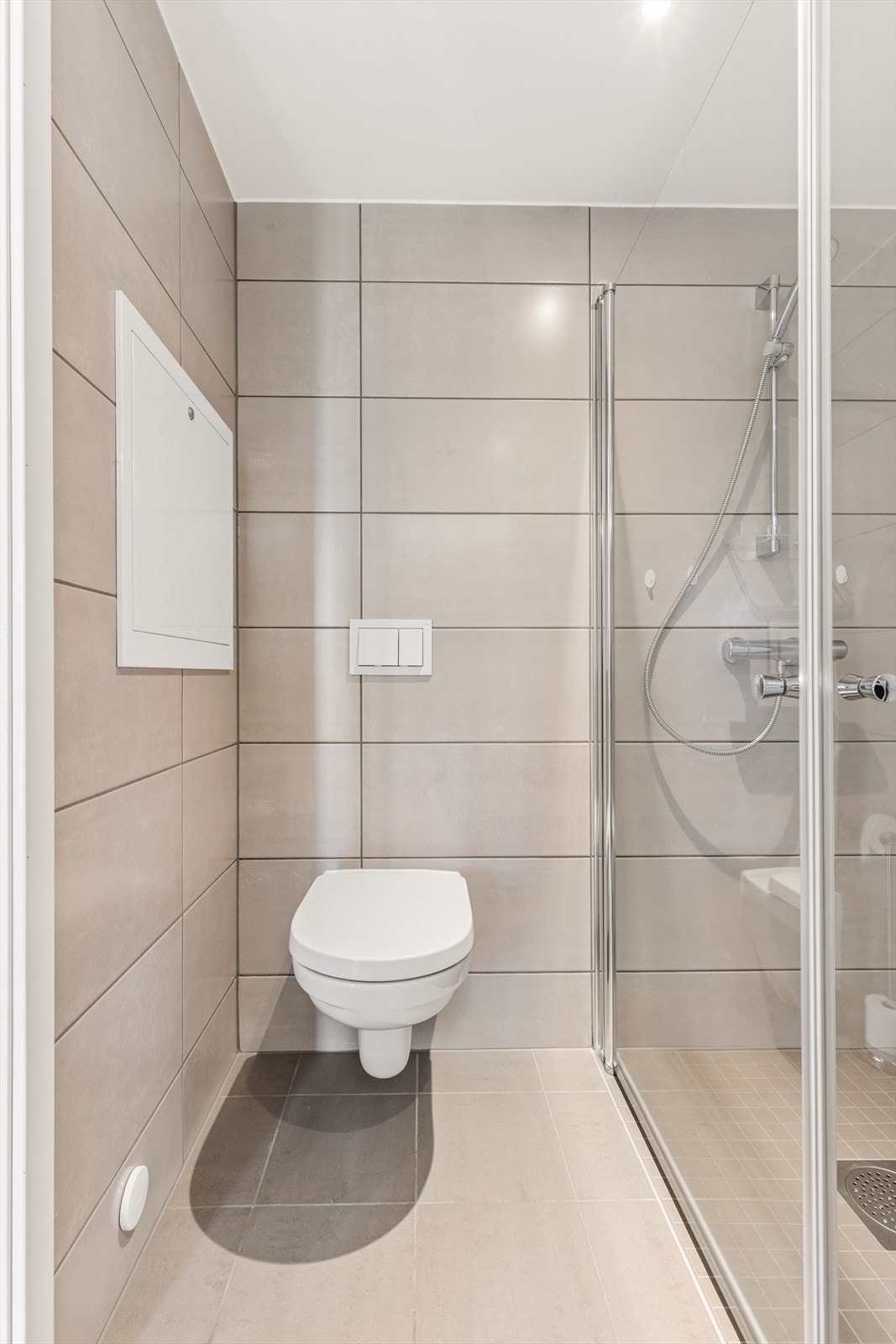 Badet har innredning med nedfelt servant, veggmontert wc, dusjvegger og opplegg for vaskemaskin. Galleribilde