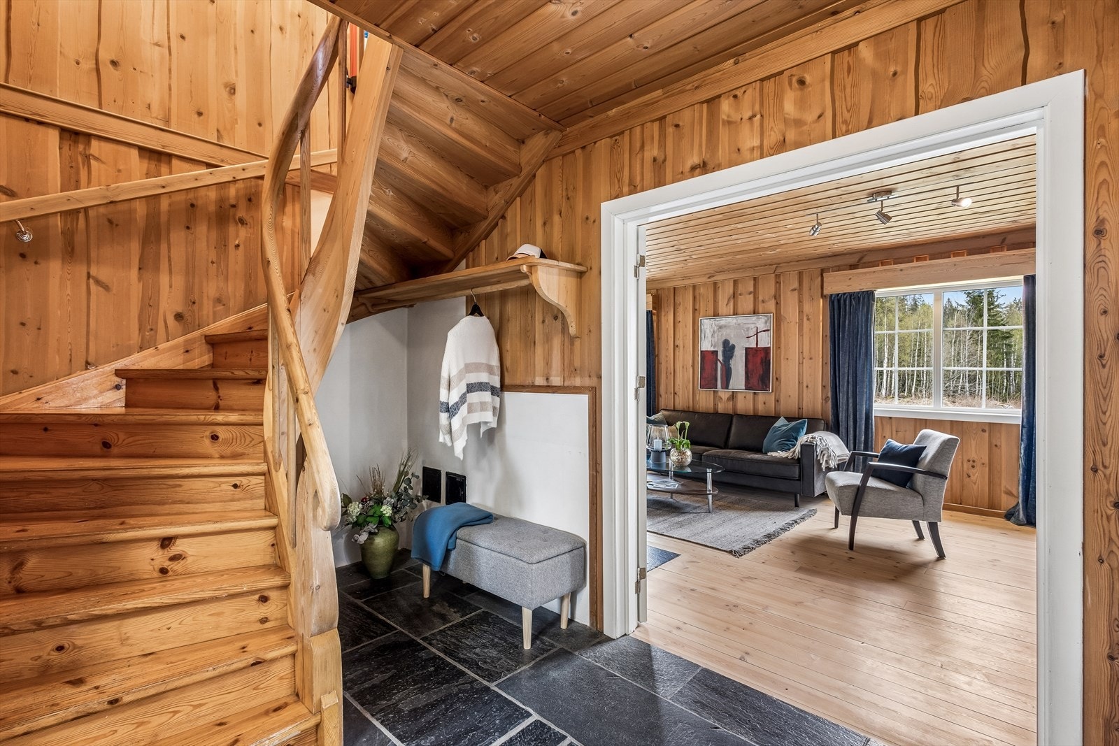 Velkommen inn! Stor hall med skifer på gulvet og lakkert tretrapp som leder opp til loftsetasjen. Galleribilde