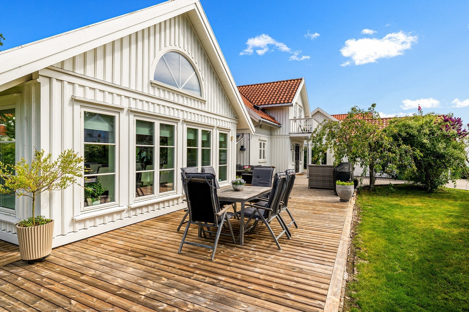Lettstelt hage med store terrasse flater, gressplen og noe beplanting. Galleribilde