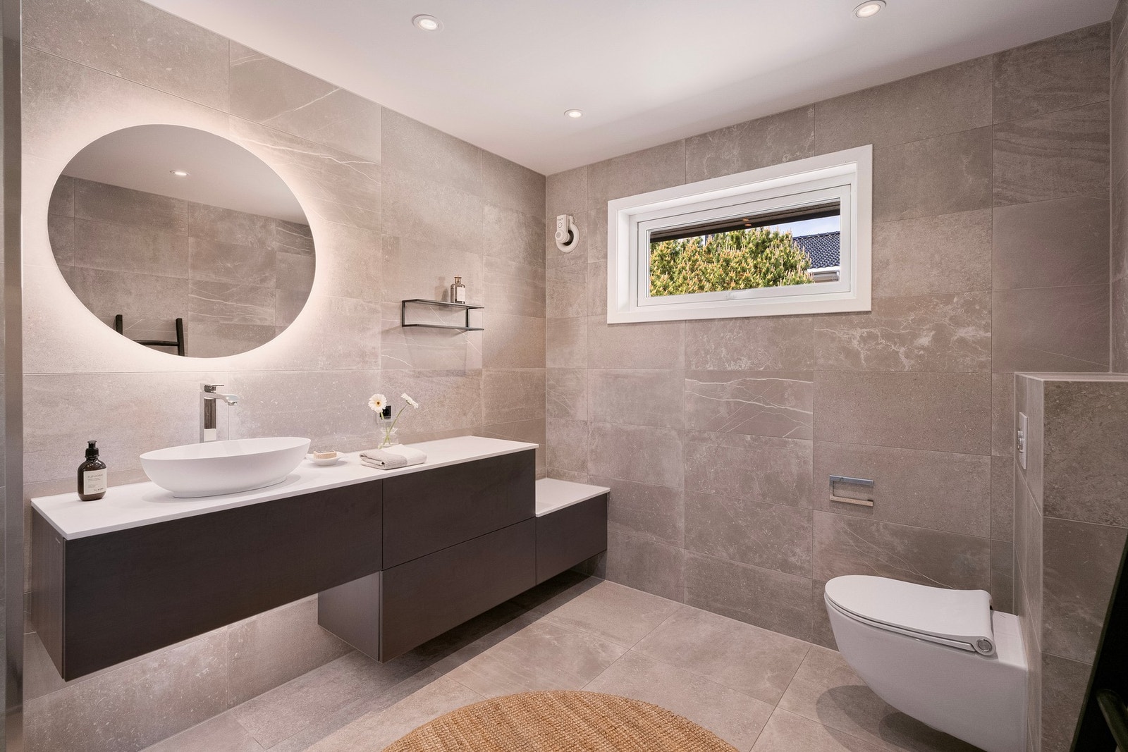 Badet i 1. etasje er er moderne og delikat med store fliser, innfelte downlights, rund speilbelysning og et stilrent uttrykk. Galleribilde