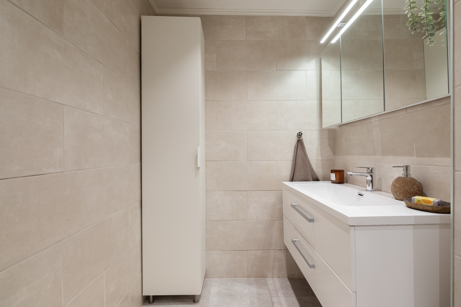 Badet fremstår moderne og pent med flislagte overflater, gulvvarme og nedsenket himling med downlights. Galleribilde