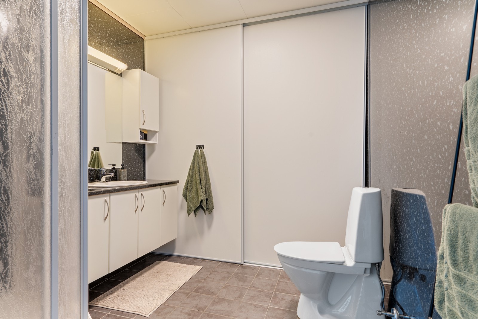 Flott baderom med opplegg til vaskemaskin bak skyvedører. Galleribilde