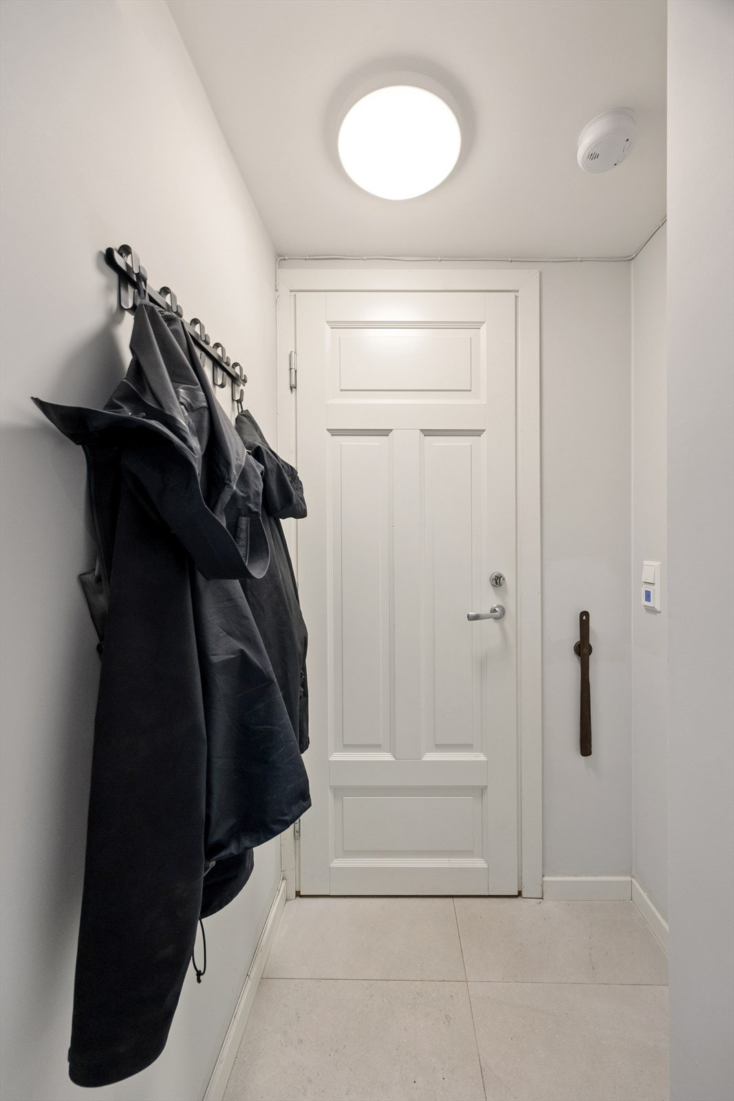 Innbydende inngangsparti med knagger på vegg og plass til enkle oppbevaringsmøbler. Entreen har lysmalte vegger og lekre flislagte gulv med varmekabel. Galleribilde