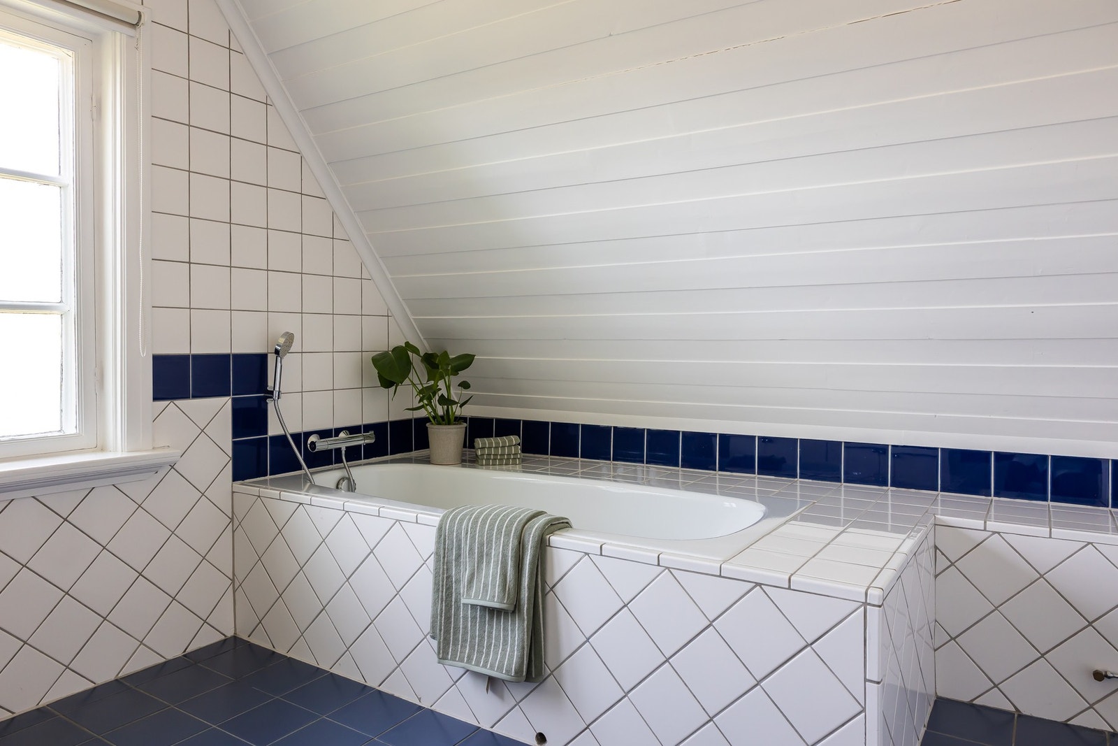 Badekar med vegghengt badekararmatur og gulvstående toalett. Naturlig avtrekksventil i himling. Galleribilde