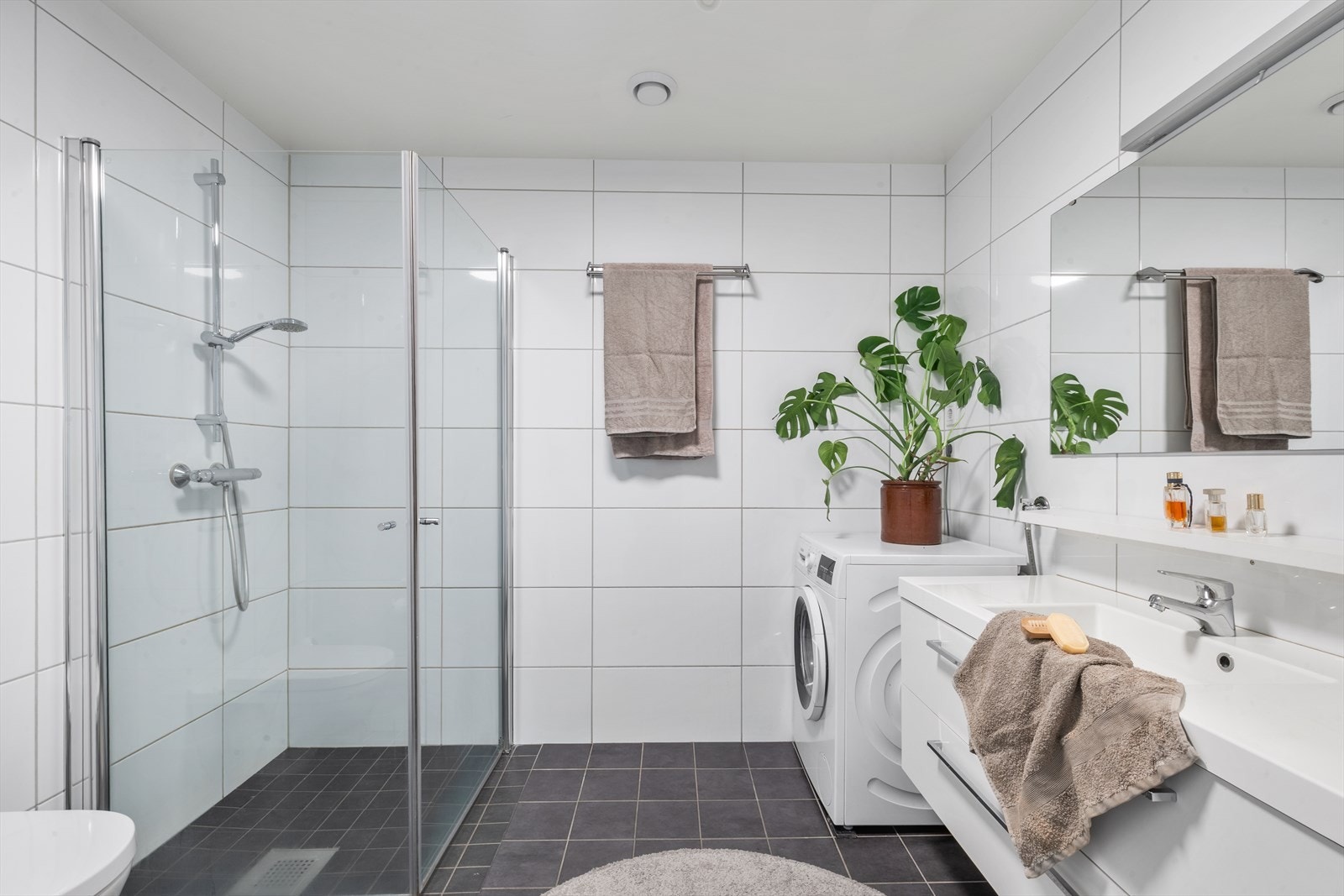 Romslig og moderne bad med flislagte overflater, dusjsone og praktisk innredning. Galleribilde