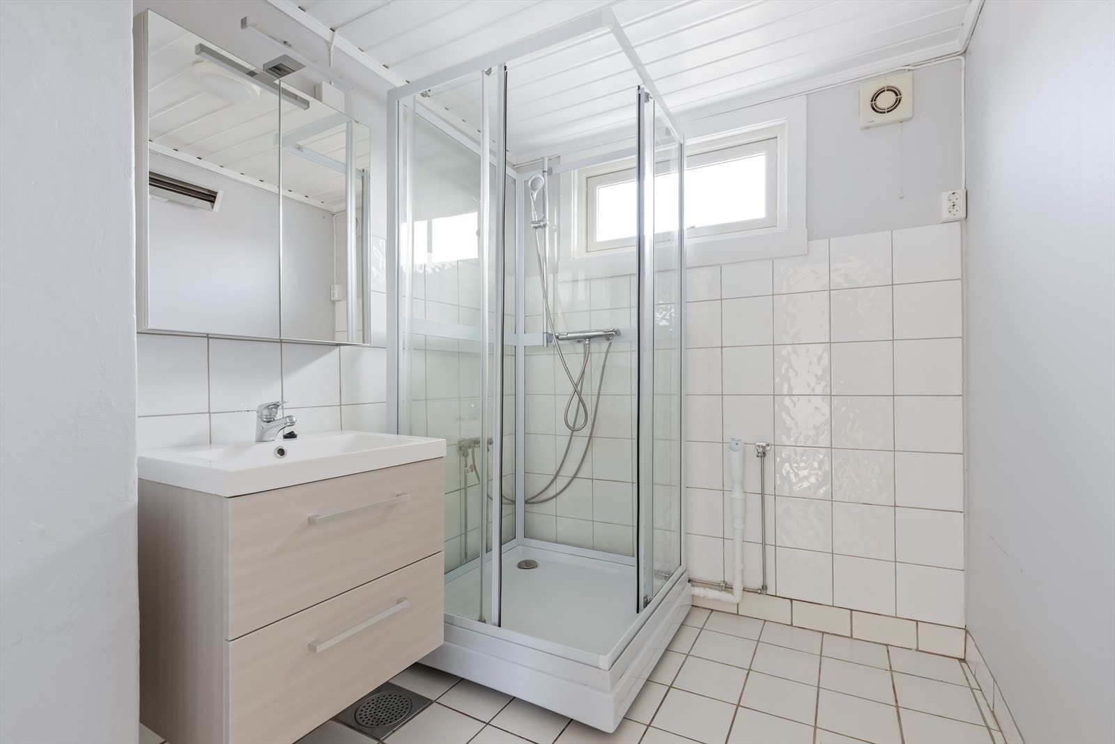 Badet er innredet med dusjkabinett, servant med skuffer og speilskap. Galleribilde