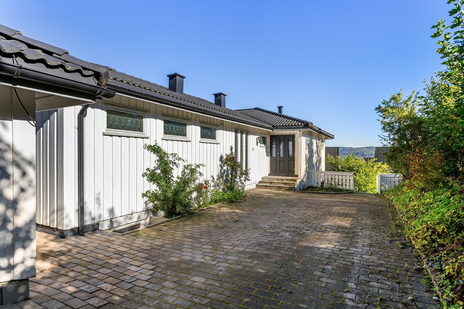 Innkjøring og gårdsplass er belagt med belegningsstein, med parkering foran garasjen. Galleribilde