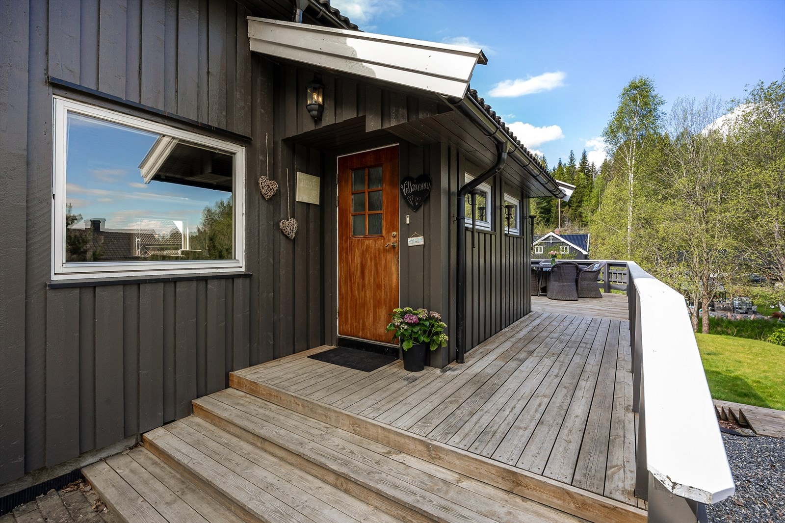 Boligen har en hyggelig adkomstterrasse i tre. Ytterdøren er overbygd på den store terrassen, utstyrt med belysning og ringeklokke. Galleribilde