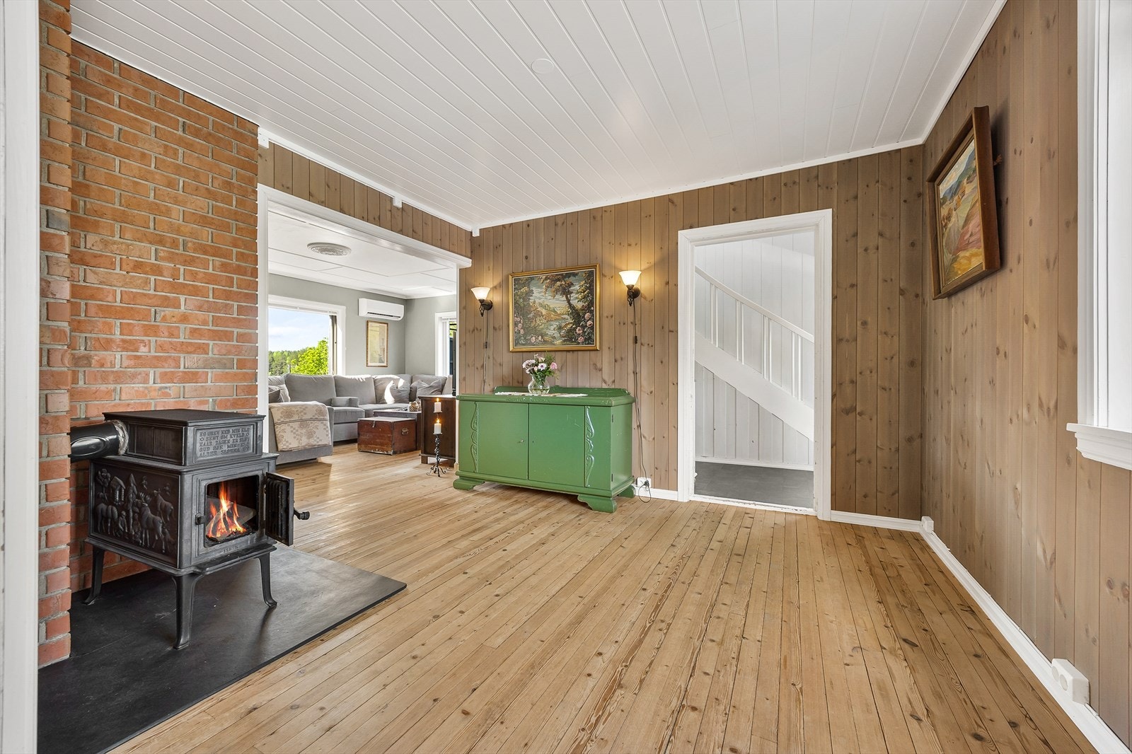 Hallen er innredet med tregulv, vedovn og beiset trepanel. Herfra er det også åpent inn til de to stuene i første etasje. Galleribilde