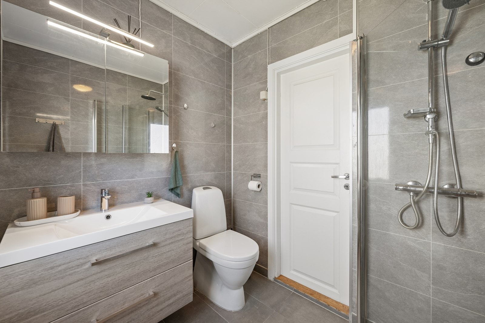 Badet ble oppgradert med nytt flislagt gulv, membran i dusjsonen og elektriske varmekabler i 2021. Galleribilde
