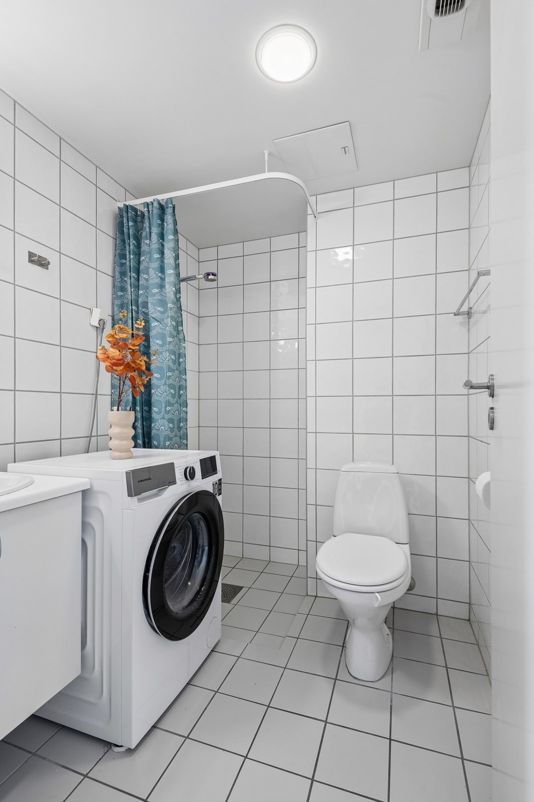 Badet er utstyrt med dusjnisje med glassdører, gulvmontert toalett og servantinnredning. Galleribilde