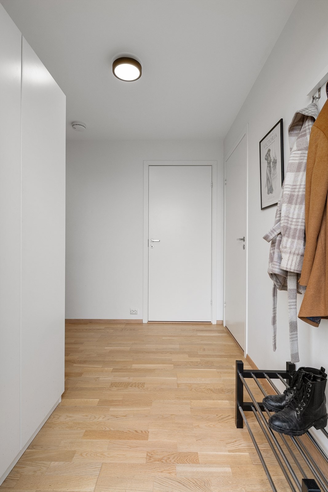 Entréen har parkett på gulv og slette, malte vegger, en standard som er gjennomgående i oppholdsrommene. Galleribilde