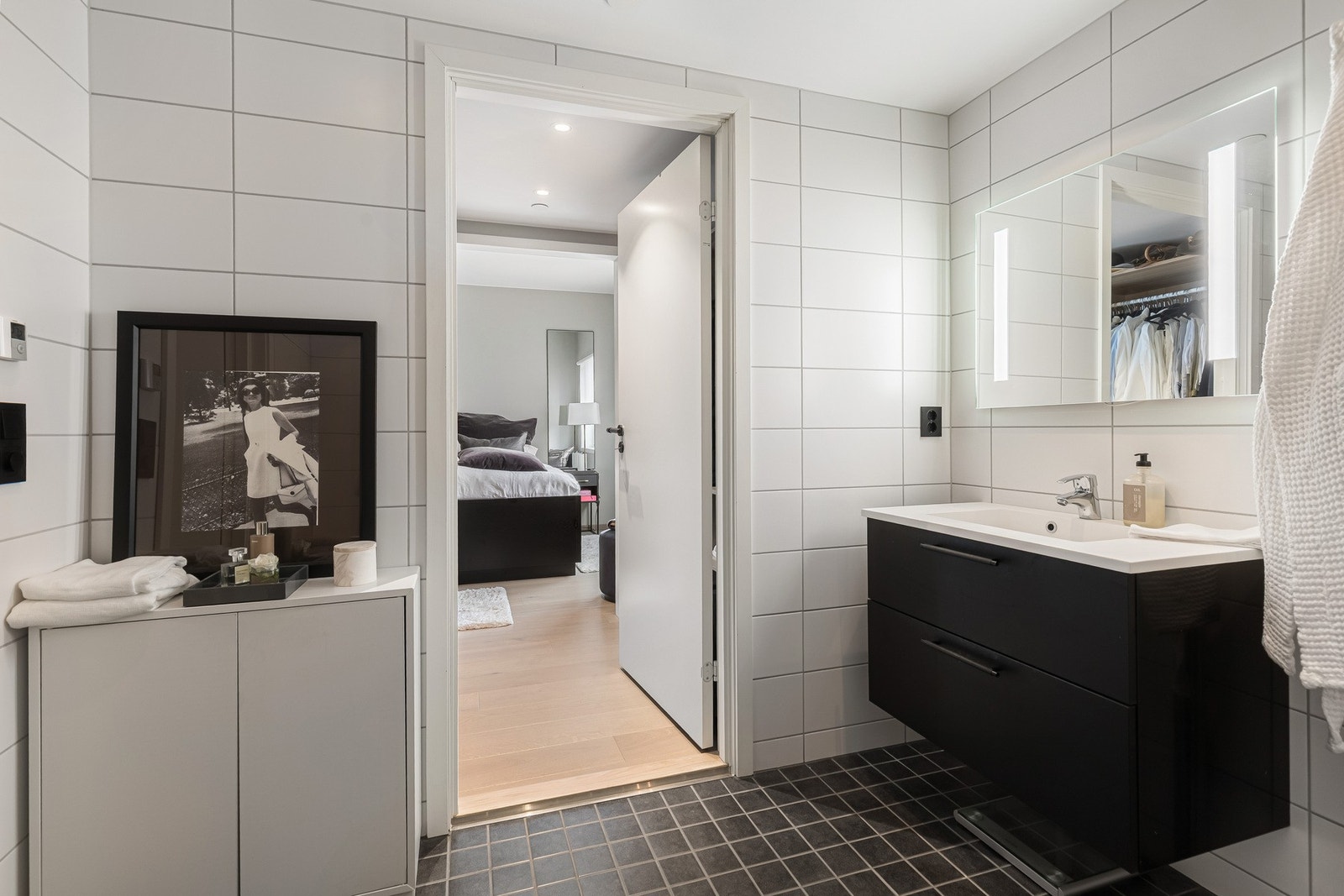 Begge badene har en nøytral og tidløs stil med hvite veggfliser, lysegrå gulvfliser og downlights i himlingen. Galleribilde