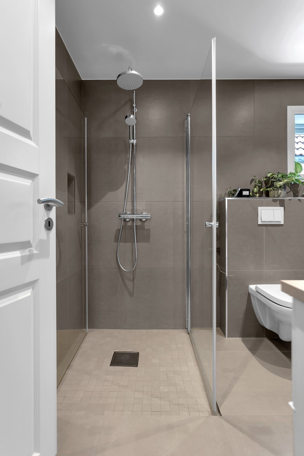 Badet har en romslig dusjsone med glassvegger og et stilrent uttrykk. Galleribilde