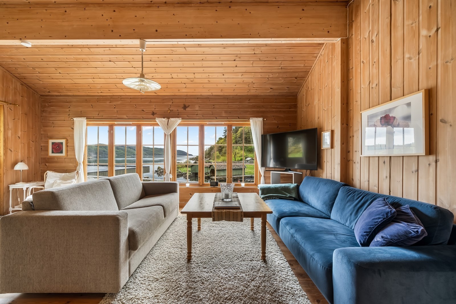 De store vinduene i stuen rammer inn utsikten mot sjøen og båthusene. Galleribilde