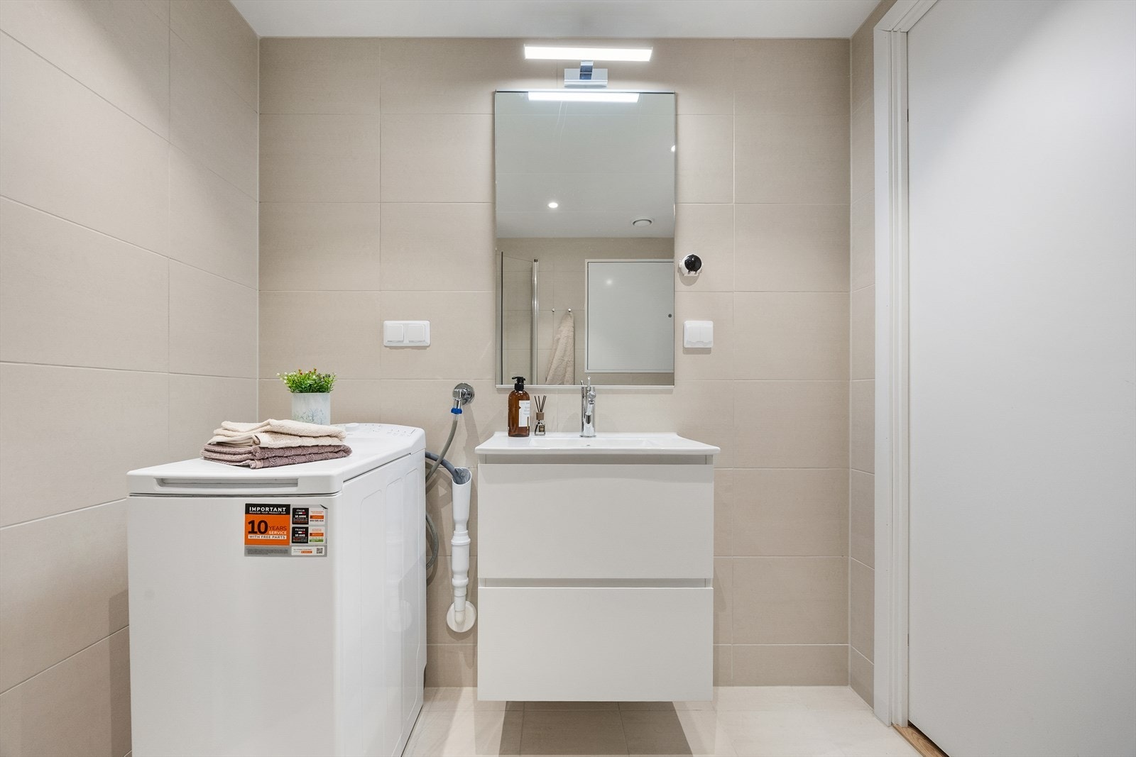 Badet er innredet med helservant på skuffeseksjon, vegghengt toalett og dusjhjørne. Opplegg for vaskemaskin. Galleribilde