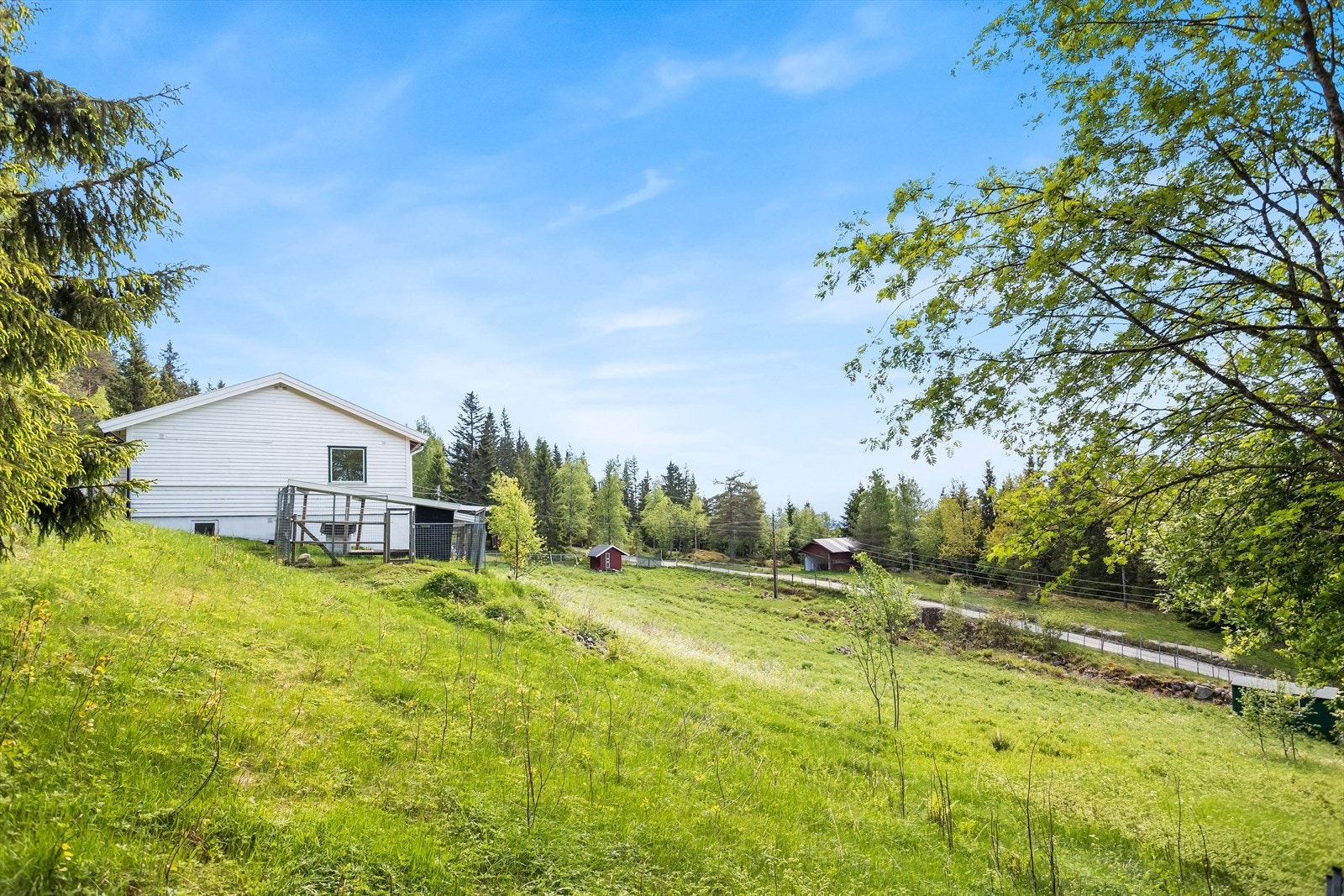 Eiendommen ligger i et skrånende terreng med en stor, opparbeidet tomt med plen og beplantning. Galleribilde