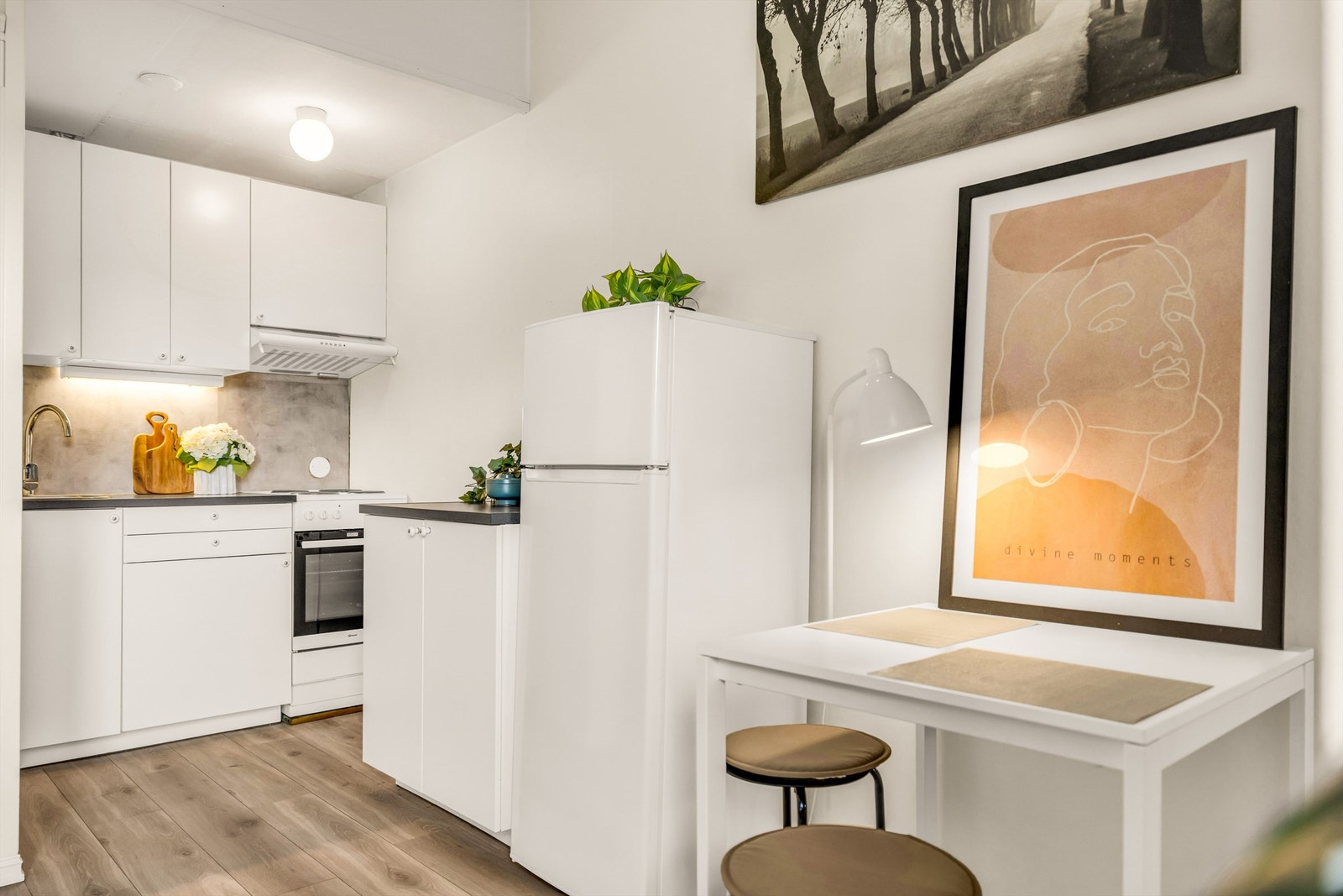 Kjøkken med moderne innredning fra 2020 med glatte fronter, benkeplate av laminat og nedfelt kjøkkenvask med armatur. Det er montert benkeskapsbelysning og stikkontakter under kjøkkenbenken. Galleribilde