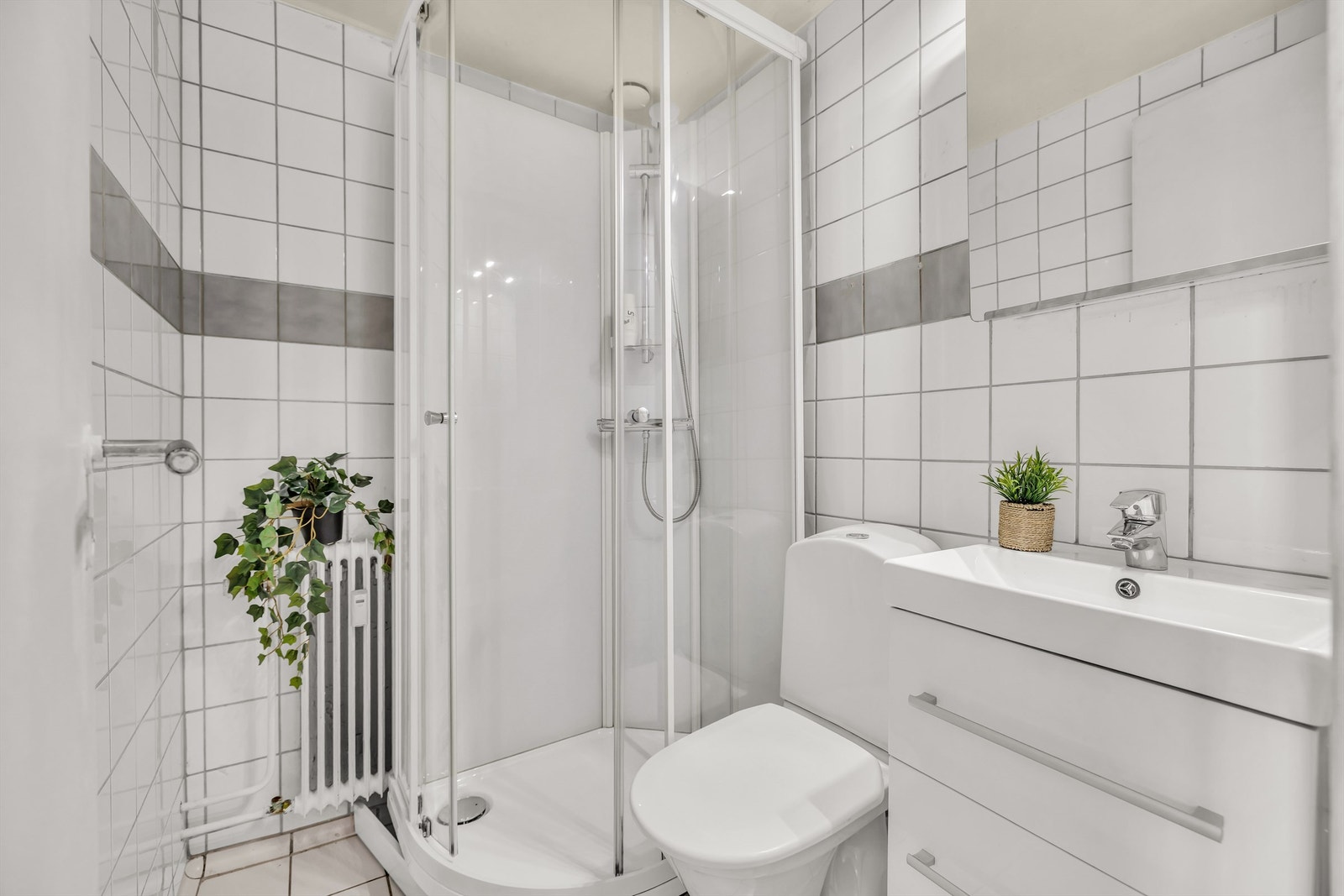 Badet ble oppgradert i 2020 med nytt dusjkabinett, nytt toalett, vegghengt servantinnredning med ovenpåliggende servant og speilskap med overlys. Galleribilde