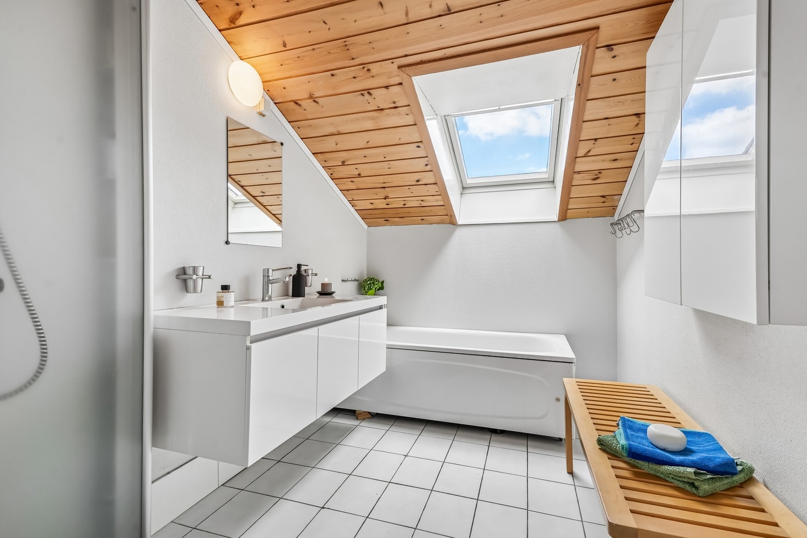Lyst bad med fliser på gulvet og varmekabler. Innredet med nyere servantinnredning og vegghengt skap, speil og badekar. Galleribilde
