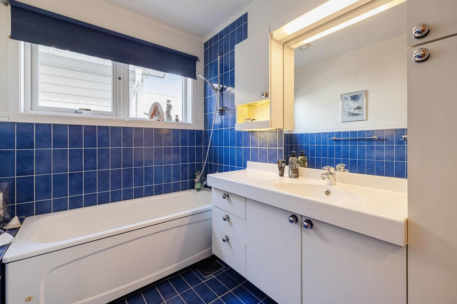 Badet er utstyrt med toalett, badekar med dusj, samt baderomsinnredning med servant og speil. Galleribilde