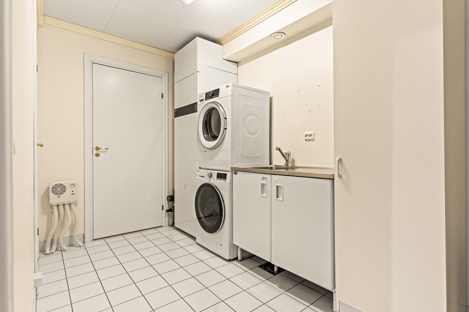 Praktisk vaskerom med flislagt gulv med gulvvarme og opplegg for vaskemaskin. Her er også boligens avtrekksvarmepumpe. Galleribilde