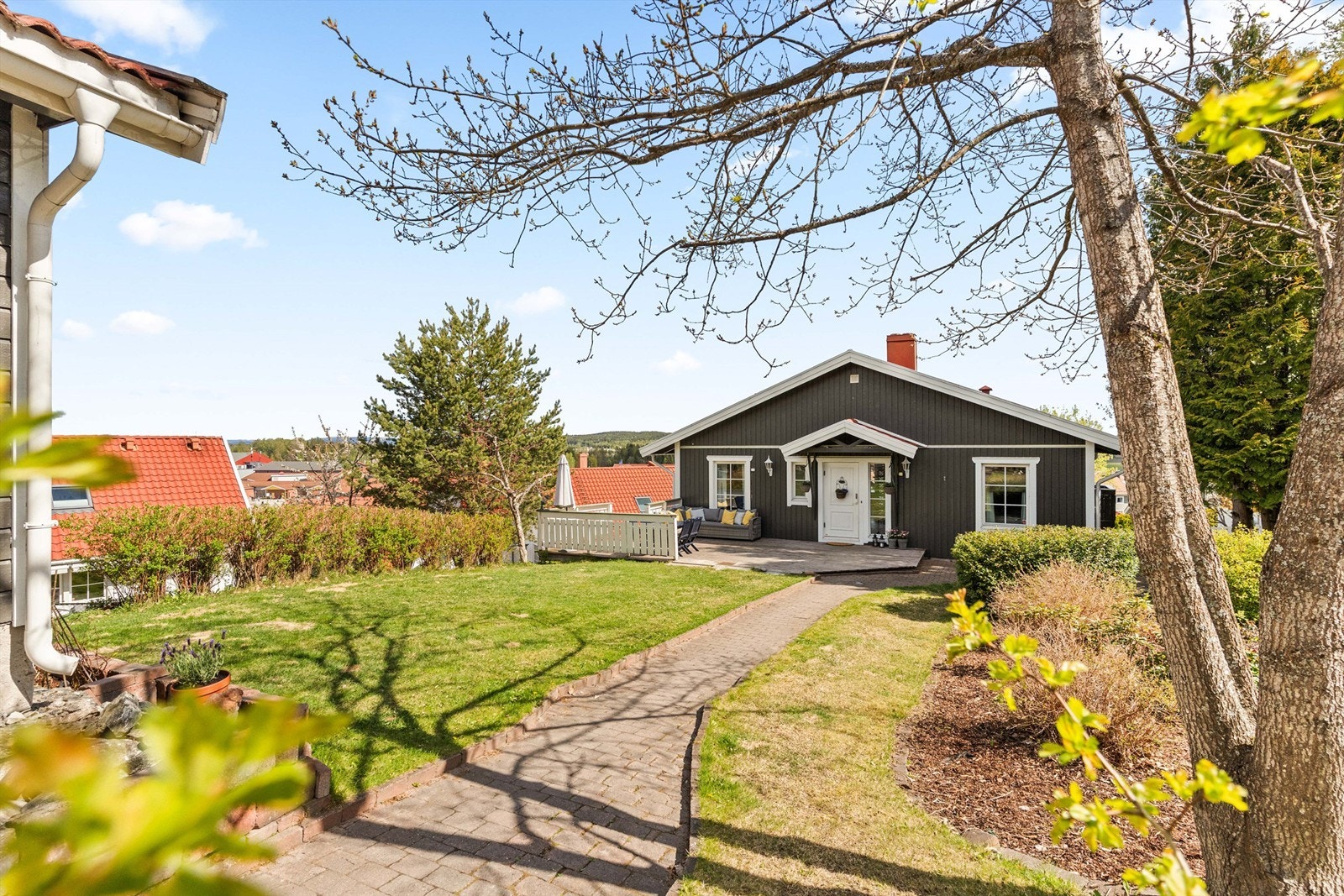 Tomten er opparbeidet med plenarealer, beplantning og gangsti av belegningsstein. Galleribilde